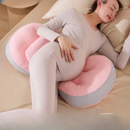 A pregnant woman comfortably resting with a C-shaped pregnancy pillow, designed to provide full-body support for the belly, lower back, and hips. Made from breathable, hypoallergenic fabric, this ergonomic pillow promotes healthy posture, reduces pressure on the spine, and enhances sleep quality. Perfect for sleeping, lounging, or postpartum nursing.
